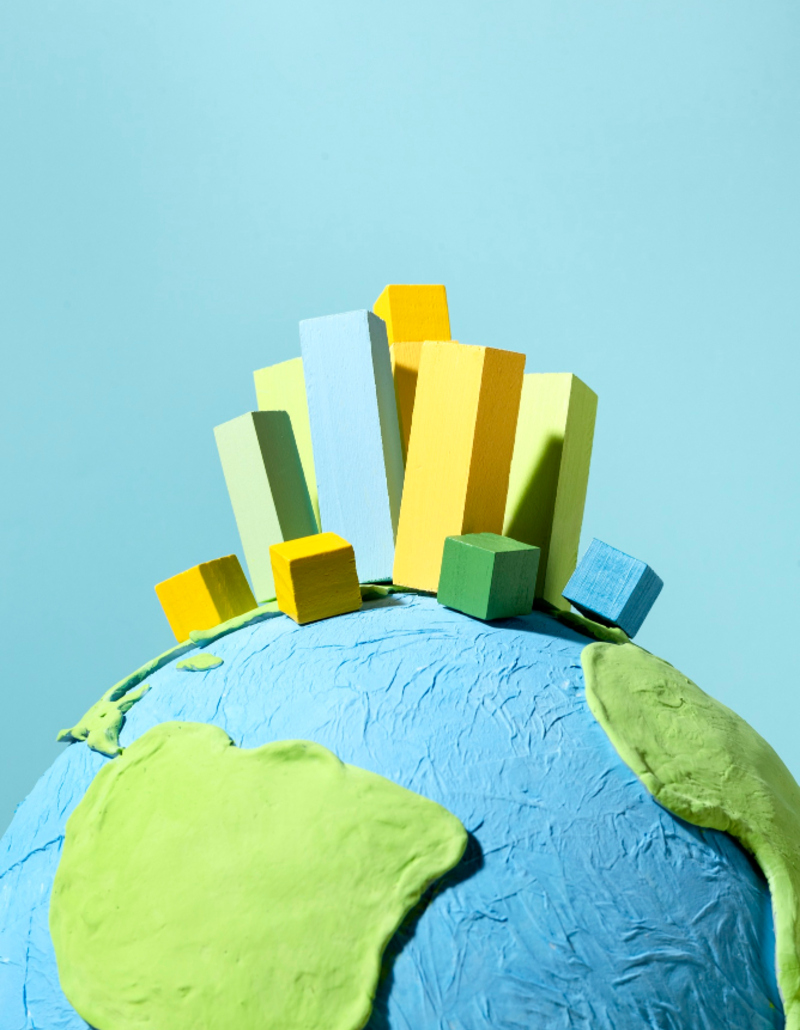 Colourful wooden bar chart blocks on a handmade clay globe – representing climate action and sustainability data