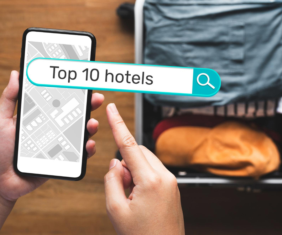 Traveller searching for top 10 hotels on a smartphone with a suitcase in the background
