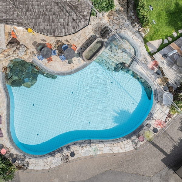 Aerial view of the curved outdoor pool and garden at paloria apartments & sport in Lagundo, South Tyrol